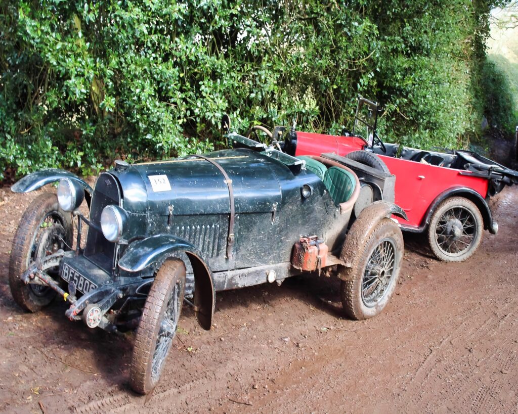 Two vintage cars parked on mud track
